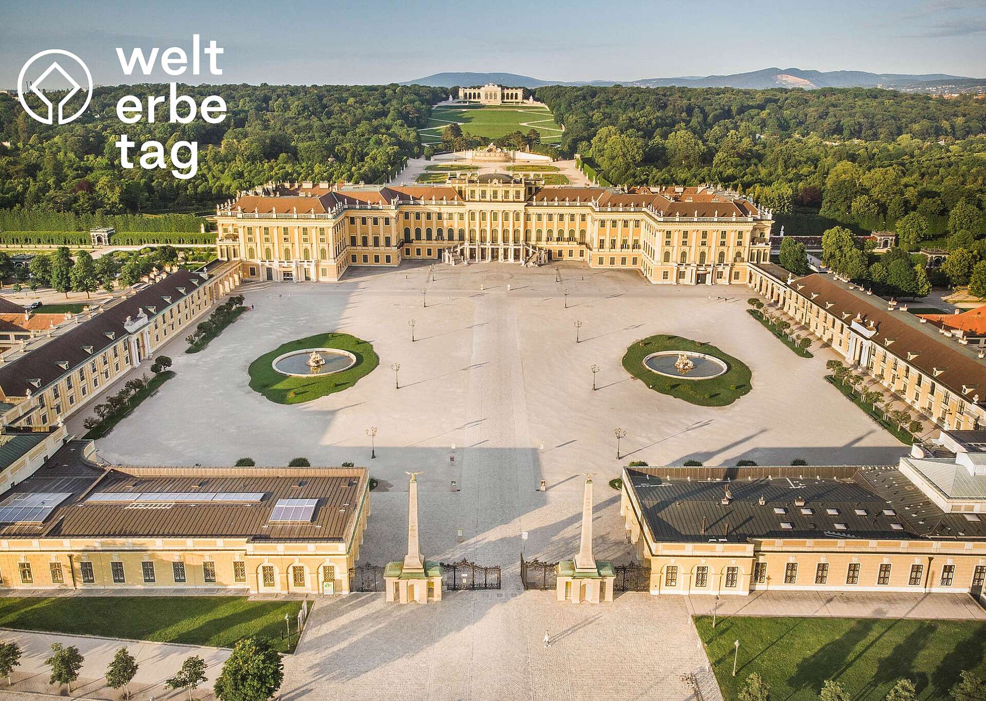 Blick von oben auf Schloss Schönbrunn mit Welterbelogo links oben